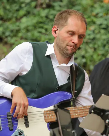 Claudio Becker-Foss spielt einen blauen E-Bass.