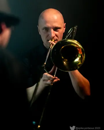 Jan Sören Damköhler spielt Posaune vor dunklem Hintergrund.
