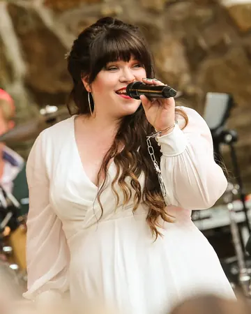 Jana Meyerdierks singt im weißen Kleid, hinter ihr die Band.