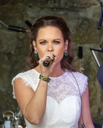 Rachelle Sondeijker singt im weißen Spitzenkleid ins Mikrofon.